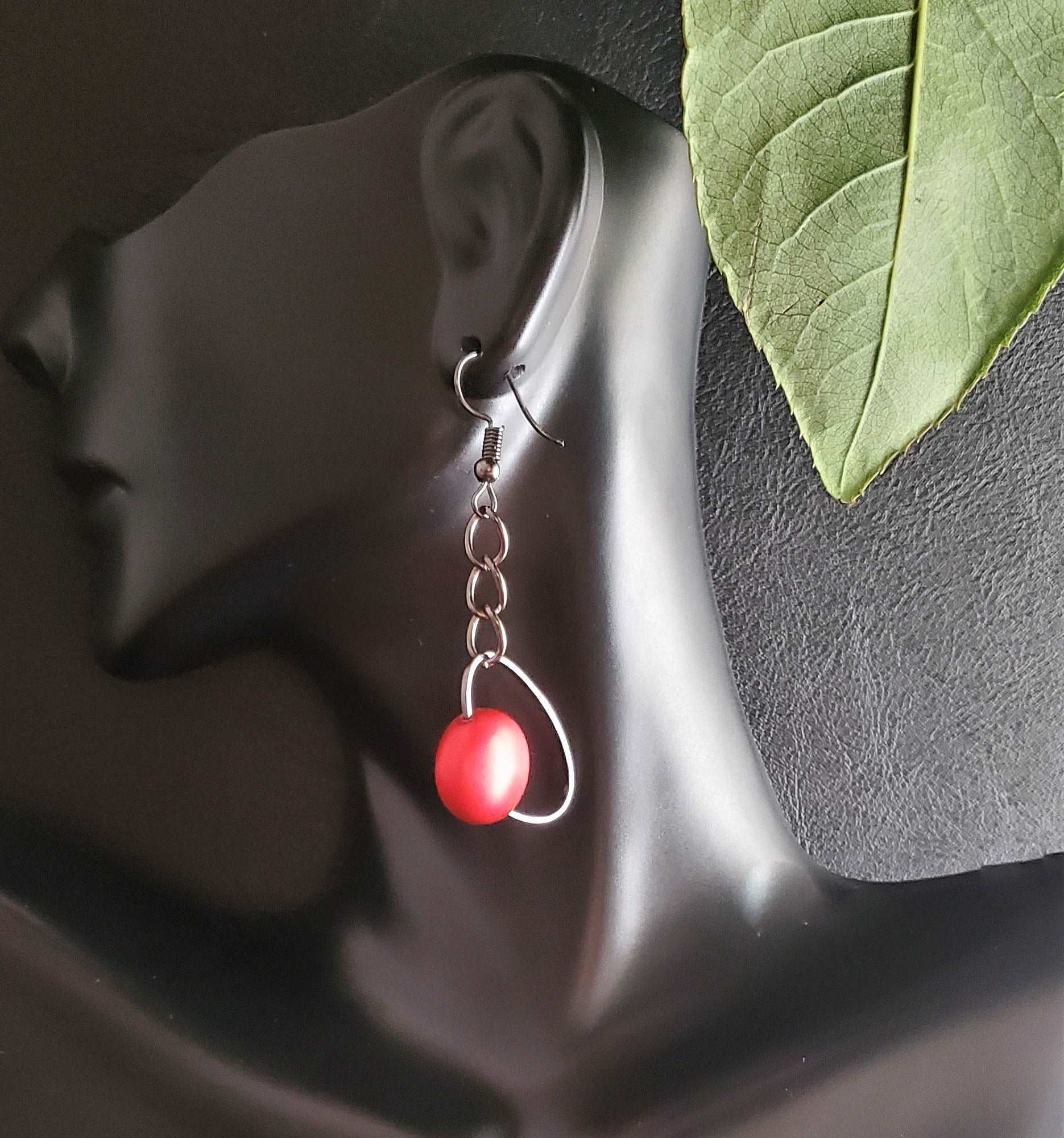 photo of red earrings with green leaf on a bust, Ruby Chain Dangle Earrings, handmade earrings, earrings on black background